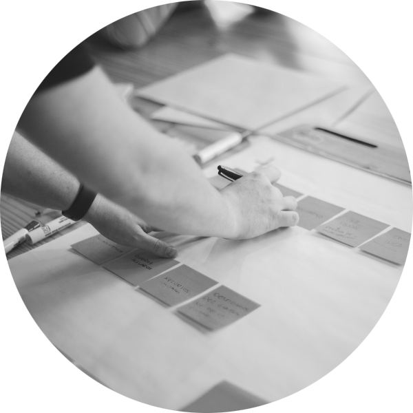 A person writing on and laying out sticky notes on a large sheet of paper on a desk