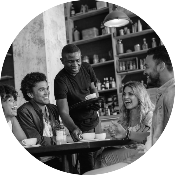 A group of smiling people enjoying coffee after a meal being served by a waiter