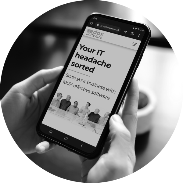 Hands holding a mobile phone and looking at the Redox Software home page