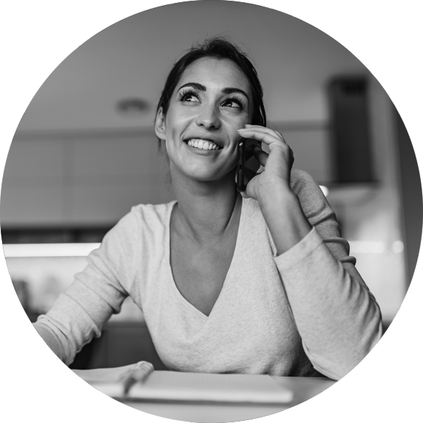 A happy, smiling woman on a phone call making notes in her diary