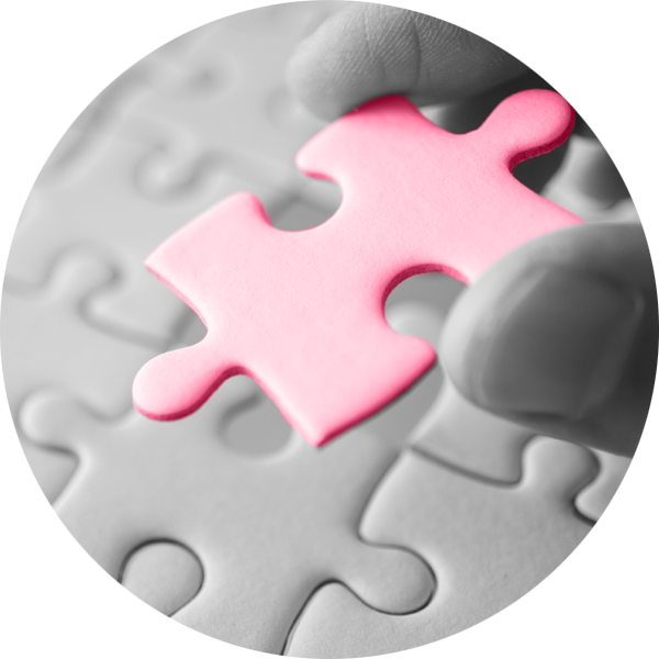 A single pink jigsaw piece being put into a jigsaw puzzle