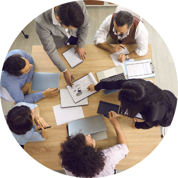 A top-down view showing a team of colleagues sitting around a meeting table