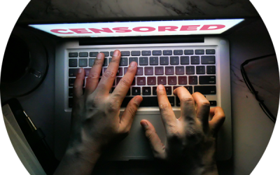 A laptop in a dark room showing the word censored on the screen